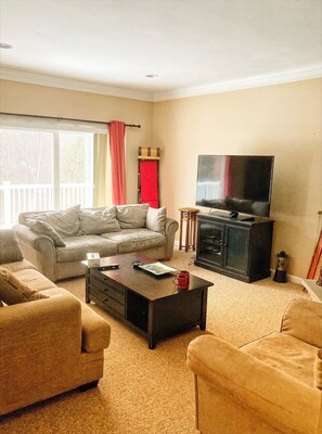 A living room with a sofa, a coffee table, a TV, and a fireplace.