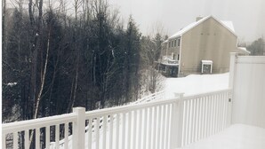 Une maison avec une clôture blanche, entourée d’arbres et recouverte de neige.