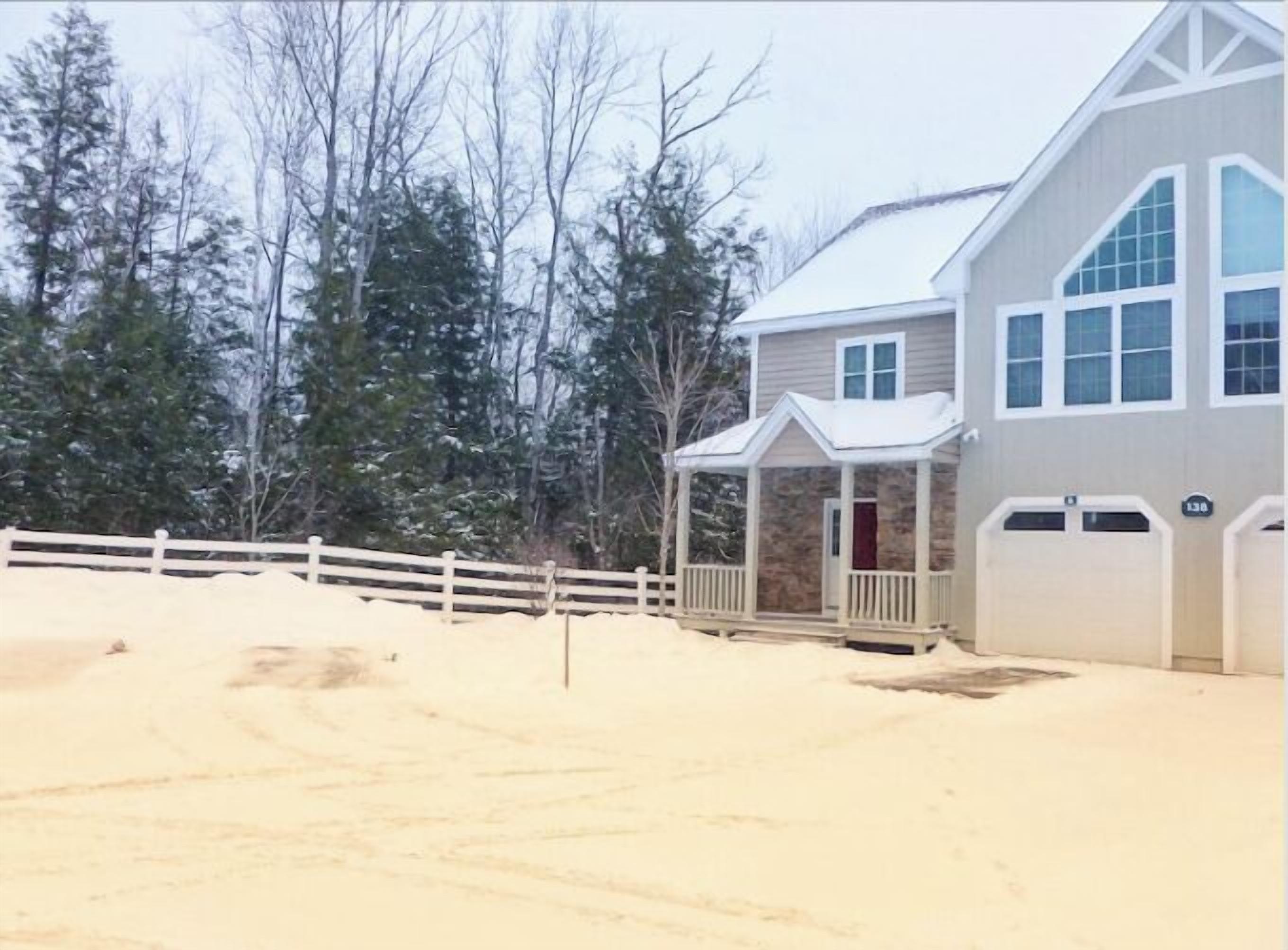 A two-story house with a stone facade, a porch, and a fenced yard.