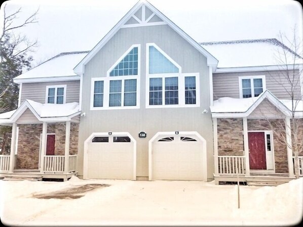 A two-story house with a gabled roof, two garage doors, and a stone facade.