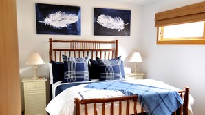 A bedroom with a wooden bed frame, two bedside tables with lamps, and two feather artwork on the wall. - Immaculate Updated Condo, 5 Minutes from Skiing!  (Wilson)