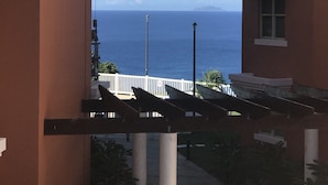 En vy över havet genom en gång mellan byggnaderna, med ett vitt staket och gatlyktor.