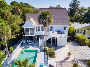 A two-story house with a pool, deck, and outdoor seating area.