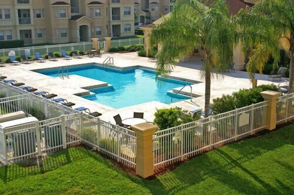 A rectangular pool with a white fence, surrounded by lounge chairs and palm trees. - 2 Bedroom 2 Bathroom Condo Near Disney, Florida (Davenport)