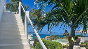 A staircase leading to a pool area with a view of the ocean.
