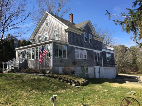 A two-story house with a prominent American flag, a garage, and a stone retaining wall.