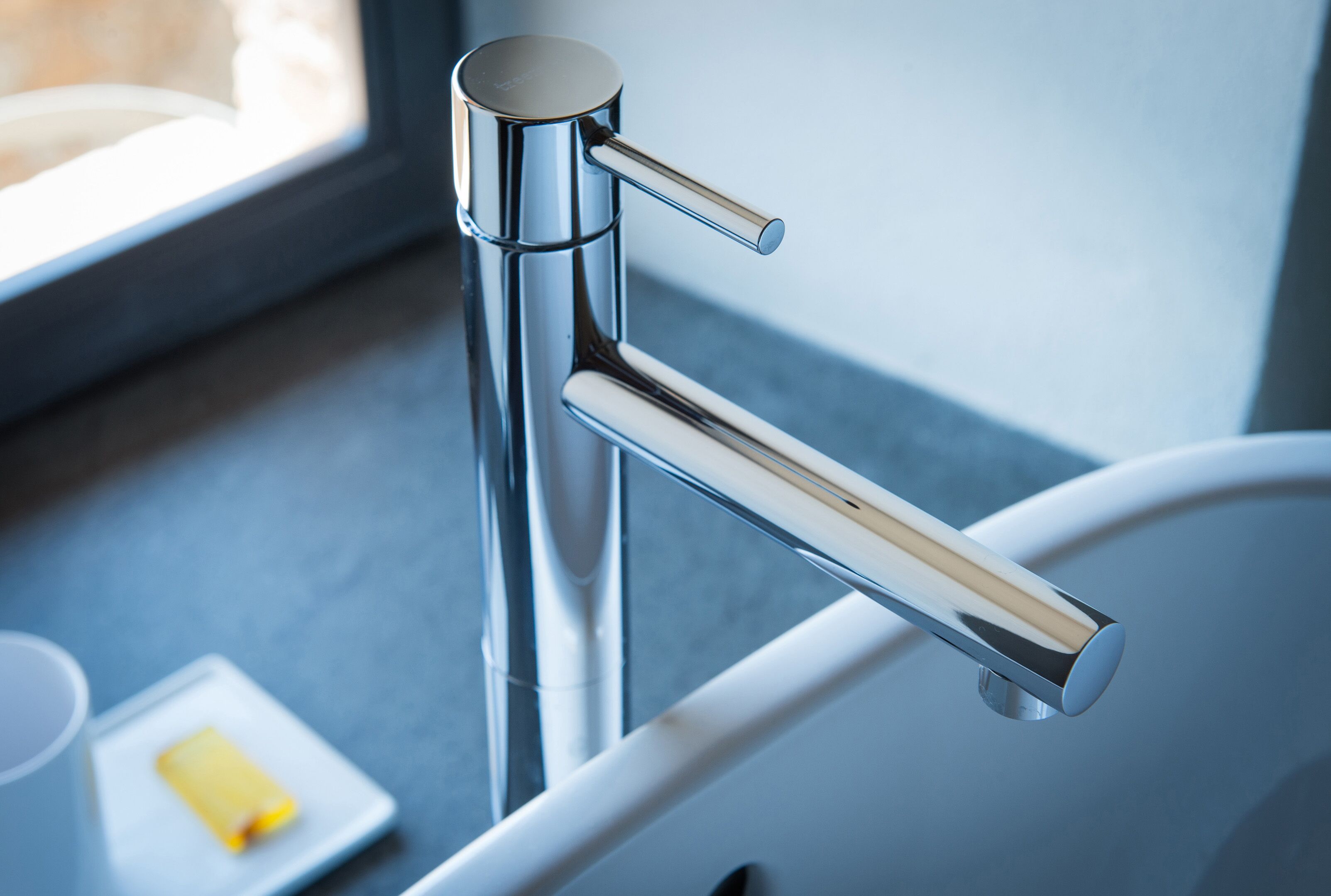 A modern bathroom with a chrome faucet and a white bathtub.