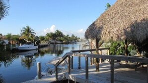 A wooden dock with a thatched-roof structure, a calm waterway, and boats docked. - Waterfront Cottage, pool, walking to the Beach and Lauderdale by the Sea Center (Lauderdale-by-the-Sea)
