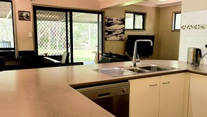 A modern kitchen with a large island, stainless steel sink, and a dishwasher.