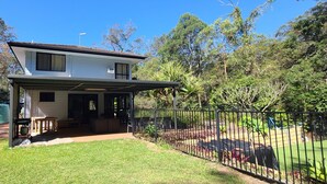 A two-story house with a covered patio and a fenced backyard.