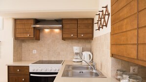 A modern kitchen with wooden cabinets, a built-in oven, a coffee maker, and a sink. - Mykonos Old Harbor Front Suite with Balcony  (Mikonos)