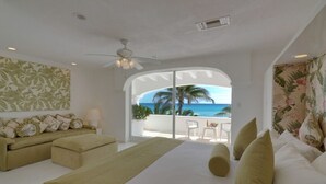 Een slaapkamer met een groot bed, een bank en uitzicht op de oceaan.