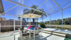 A covered patio with a table and chairs, a pool, and a view of the surrounding landscape. - Secluded Luxury Pool Home, Close to Disney w/ Oversized pool  Special offers now (Kissimmee)