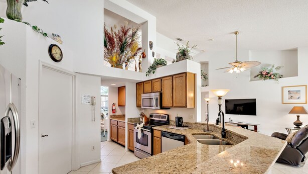 A modern kitchen with granite countertops, wooden cabinets, and a built-in microwave. - Secluded Luxury Pool Home, Close to Disney w/ Oversized pool  Special offers now (Kissimmee)