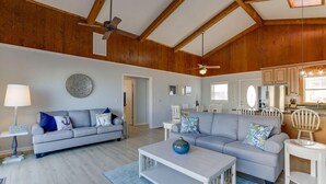 A spacious living room with a grey sofa, a white coffee table, and a ceiling fan. - OCS4 Semi-Ocean-Front Home with Gorgeous Views (Nags Head)