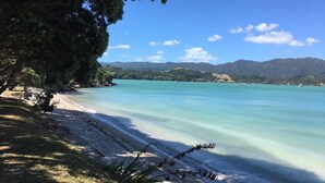 Una spiaggia con acque cristalline turchesi, una riva sabbiosa e delle colline sullo sfondo.