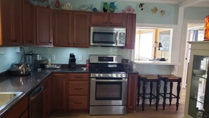 A kitchen with wooden cabinets, a microwave, an oven, and a sink. There are decorative items on the wall and a window with a view.