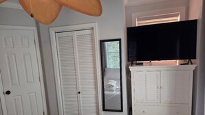 A bedroom with a bed, a television, a wardrobe, and a door.