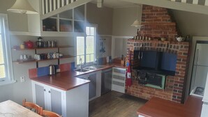 A kitchen with a brick oven, wooden cabinets, and a dining area with a table and chairs.