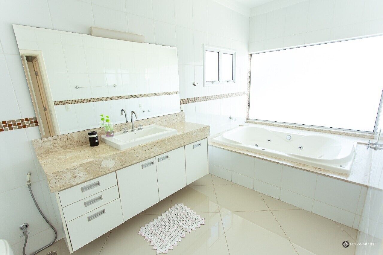 Une salle de bain moderne avec un grand miroir, deux lavabos, une baignoire et une fenêtre.