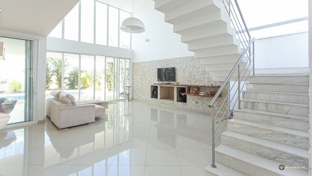 Un salón amplio con un sofá blanco, una chimenea y una escalera.