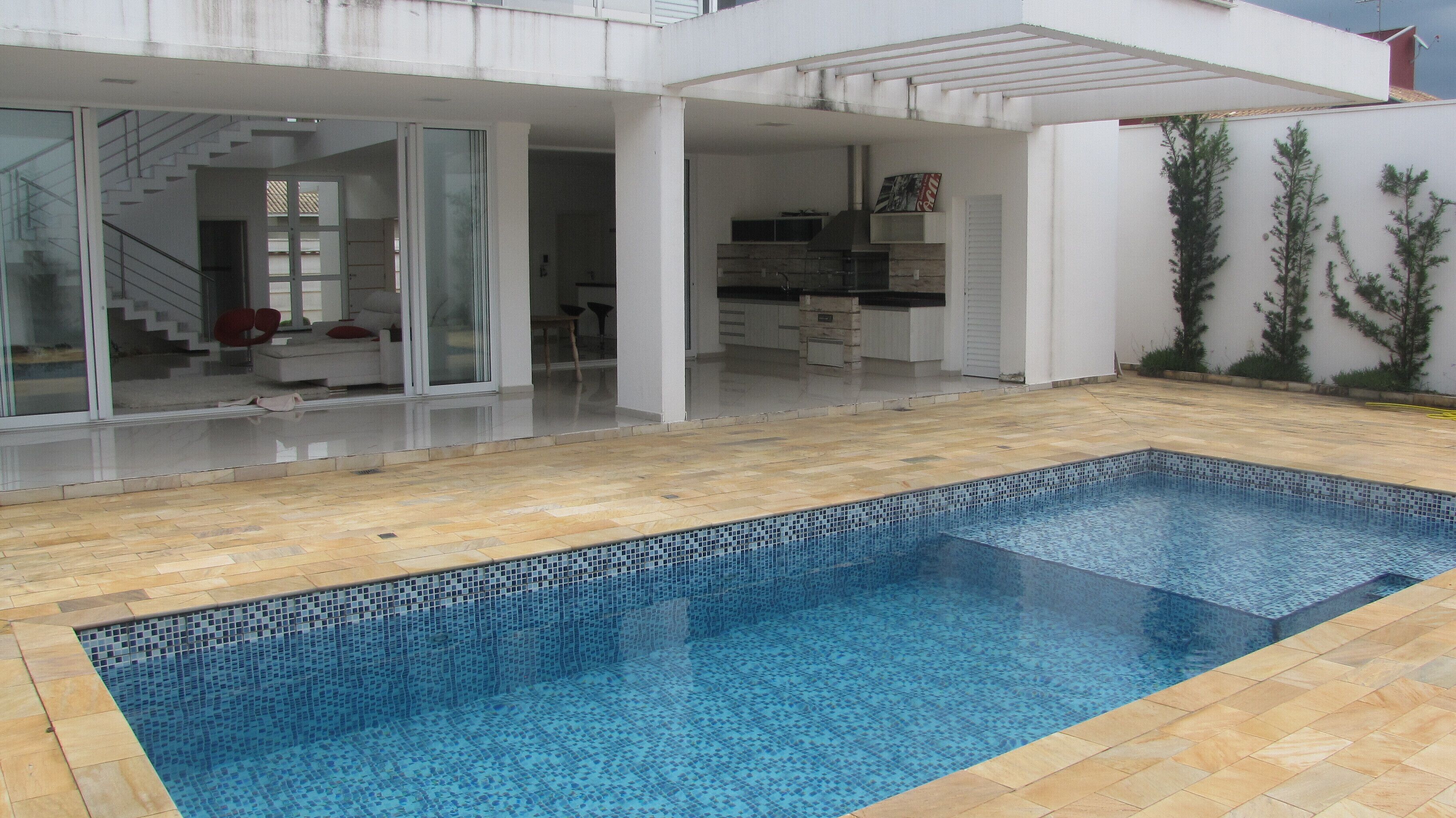 Une maison moderne dotée d’une piscine, d’un patio couvert et d’un espace cuisine.