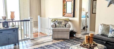 Ein geräumiges Wohnzimmer mit großem Fenster, einem gestreiften Sofa, einem dunkelgrauen Sofa und einem gemusterten Teppich.