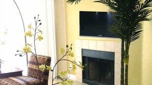 Ein Wohnzimmer mit Sofa, Couchtisch, Kamin und Fernseher.