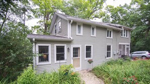 A two-story house with a front porch, a driveway, and a garden. - 3 BR/2 BA House just steps from Lake Geneva (Williams Bay)
