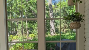 A sunroom with large windows, wicker chairs, a small round table, and a hanging plant. - 3 BR/2 BA House just steps from Lake Geneva (Williams Bay)
