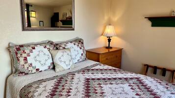 A bedroom with a bed, a dresser, a mirror, and a lamp.