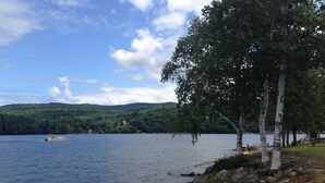 Une vue sur le lac, avec un bateau sur l’eau, une rive rocheuse et des arbres.