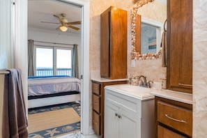 A bedroom with a bed, a ceiling fan, and a view through a window.