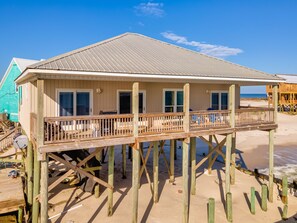 Une maison de plage en bois dotée d’un balcon, d’une terrasse et offrant une vue sur l’océan.