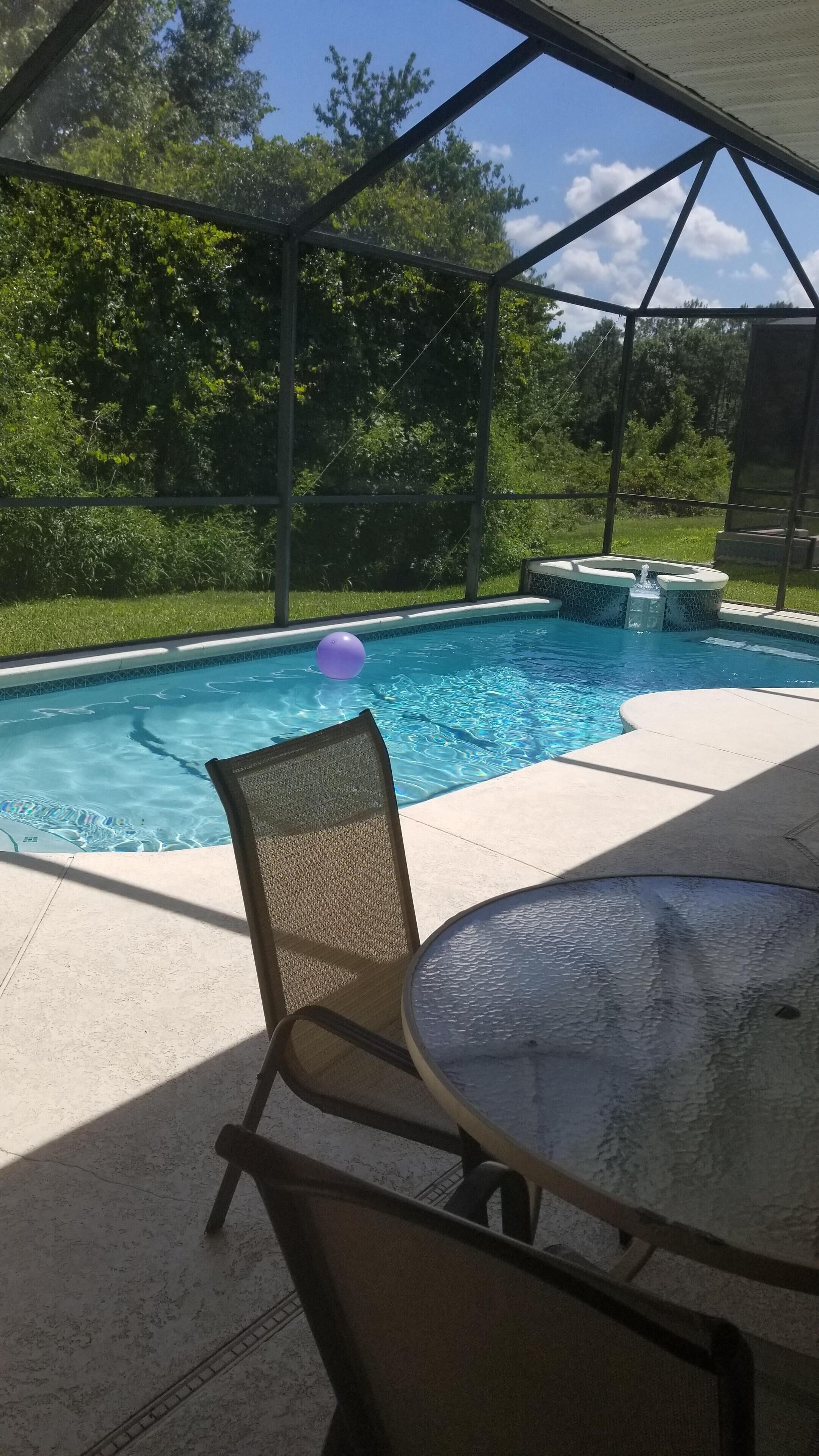 A covered outdoor area with a pool, chairs, and a table.