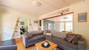 A modern living room with a grey sectional sofa, a wooden coffee table, and a staircase leading to another level. - Spirit Level Mallacoota (Mallacoota)