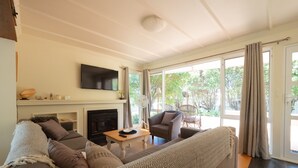 A living room with a fireplace, a television, and a sofa. - Spirit Level Mallacoota (Mallacoota)