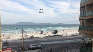 A coastal street with a beach view, pedestrian crossings, and a road with vehicles. - Apartment 30 meters from Praia do Forte beach - With beach view. (Cabo Frio)