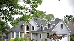 A two-story house with a stone facade, a garage, and a well-maintained lawn.