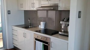A modern kitchen with white cabinets, a stainless steel stove, and a coffee maker. - Gillian's on the beachfront Port MacDonnell, the best view in town. (Port MacDonnell)