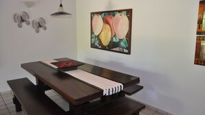 Un'area pranzo con tavolo in legno, panche, un lampadario a parete e un'opera d'arte incorniciata.