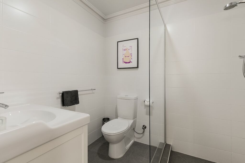 A modern bathroom with a white sink, toilet, and shower.