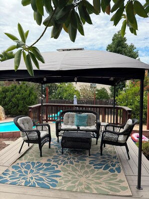 Un espace extérieur aménagé, abrité et doté de meubles en osier et d’un tapis à motifs.