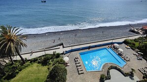 Un complexe hôtelier en bord de mer doté d’une piscine, d’une plage rocheuse et offrant une vue sur l’océan.