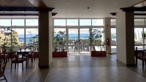 Un hall d’entrée spacieux, doté de grandes fenêtres offrant une vue sur l’océan et une montagne.