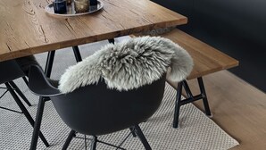 Et moderne køkken med et træspisebord, sorte stole og et fårekødsplede på en stol.