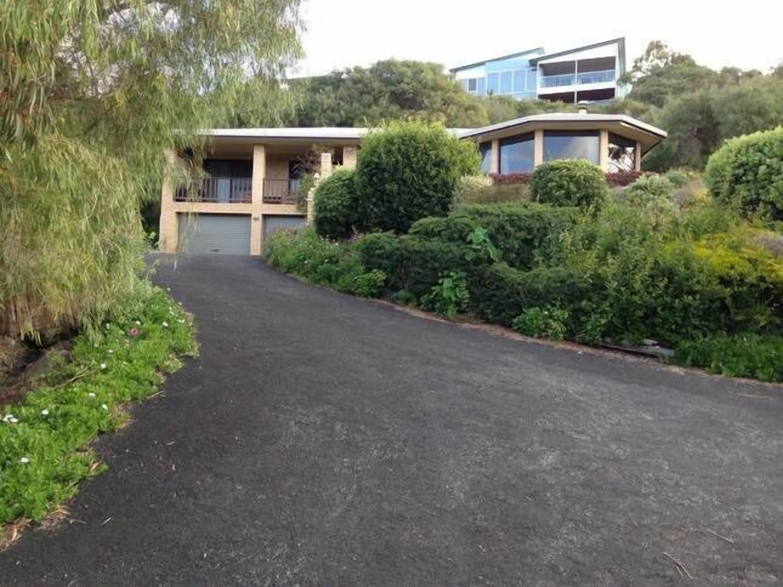 A residential area with a paved driveway leading to a house with a garage.