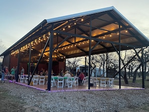 Enjoy dining or socializing under the pavilion's metal roof, surrounded by trees.