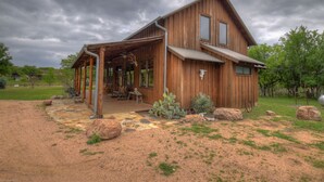 A rustic wooden house with a covered porch and a stone pathway leading to the entrance. - Lake Buchanan Lodge featuring optional Pavilion with free kayaks and canoes. (Buchanan Dam)