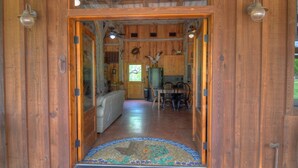 A wooden interior with a tiled entrance, a dining area with chairs, and a kitchen with a window. - Lake Buchanan Lodge featuring optional Pavilion with free kayaks and canoes. (Buchanan Dam)